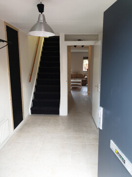 Entree met links de interne berging met wasmachine wasdroger, de trap naar de 4 kamers op de eerste en tweede verdieping en de gezamenlijke woonruimte en keuken rechtdoor.